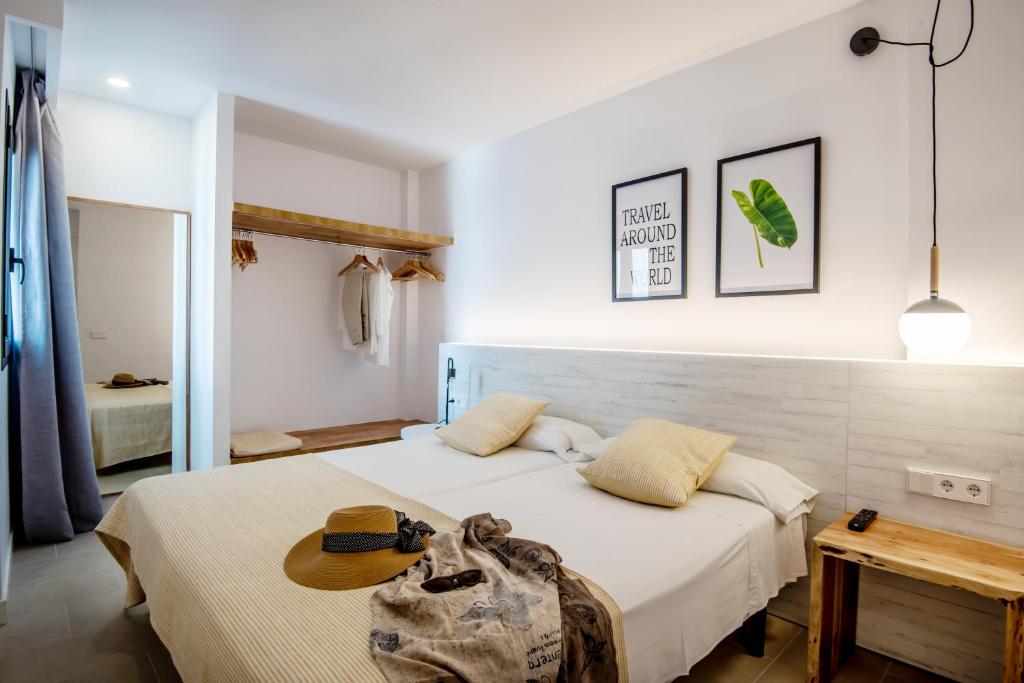 Apartamentos Es Pujols - Emar Hotels في إس بوخولس: غرفة نوم مع سرير مع قبعة عليه