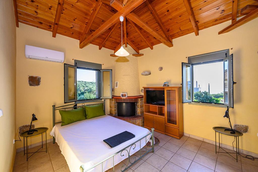 ein Schlafzimmer mit einem großen Bett in einem Zimmer mit Fenstern in der Unterkunft Alex Stone house in Kardhamili