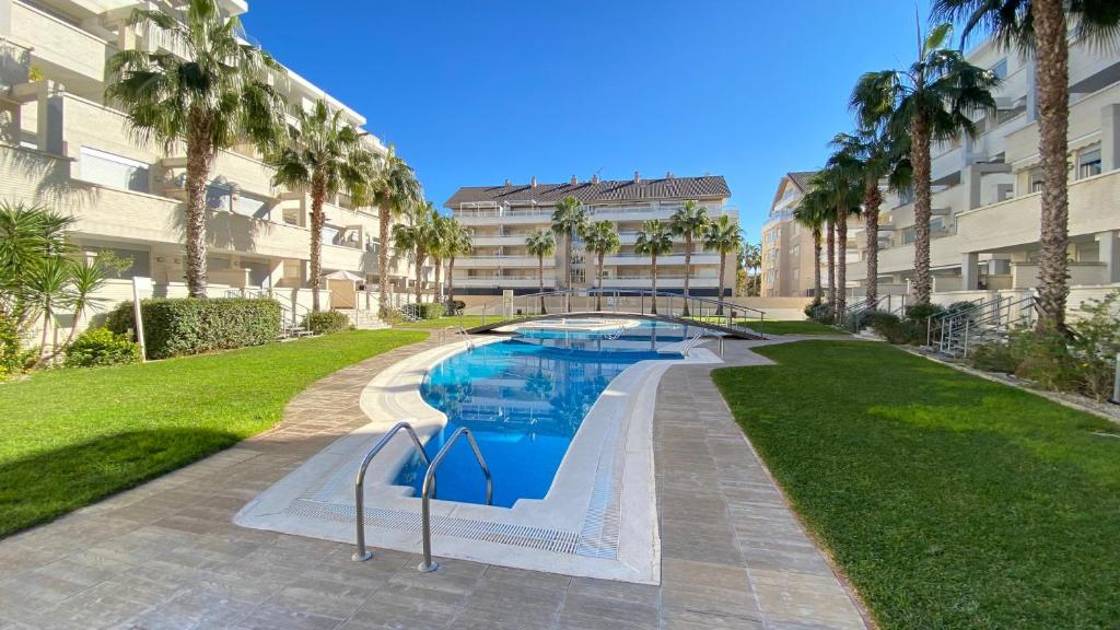 een zwembad voor een gebouw met palmbomen bij Apartamentos Elegance El Conserje in Denia