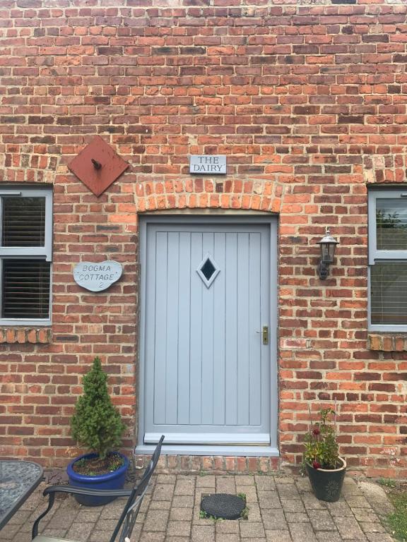 un edificio de ladrillo con una puerta blanca. en Bogma Cottages en Durham