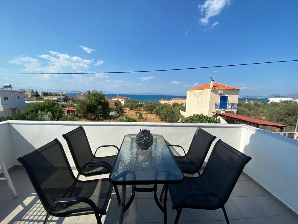 a table and chairs on a balcony with a view of the ocean at Marko's Cozy Apartment in Megalochori
