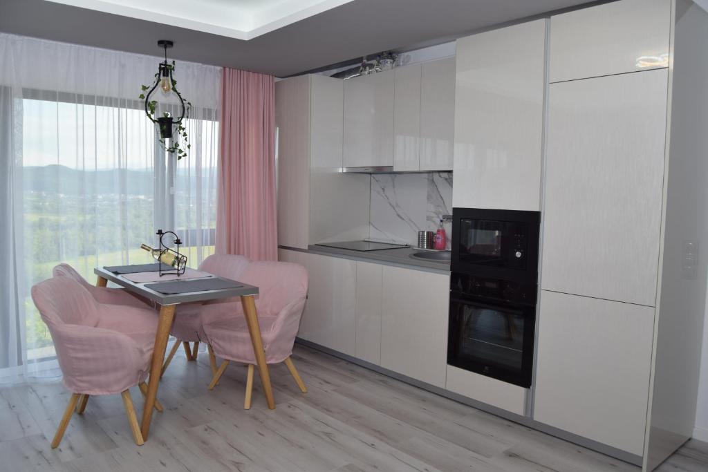 a kitchen with a table and two pink chairs in a room at Dune, apartament magic la marginea orasului in Floreşti
