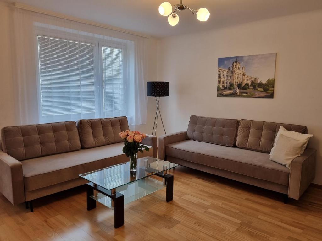 un soggiorno con 2 divani e un tavolo in vetro di Elegant Vienna Apartment a Vienna
