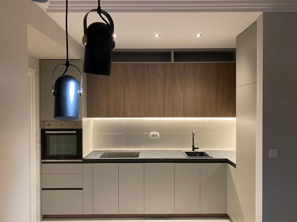 a kitchen with white cabinets and a black counter top at Apartman VT Central point in Podgorica