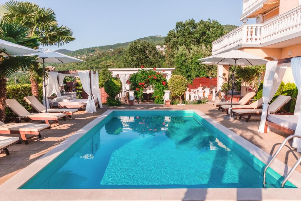 basen z krzesłami i parasolami obok budynku w obiekcie Apartments Villa Chiara Opatija w mieście Ičići