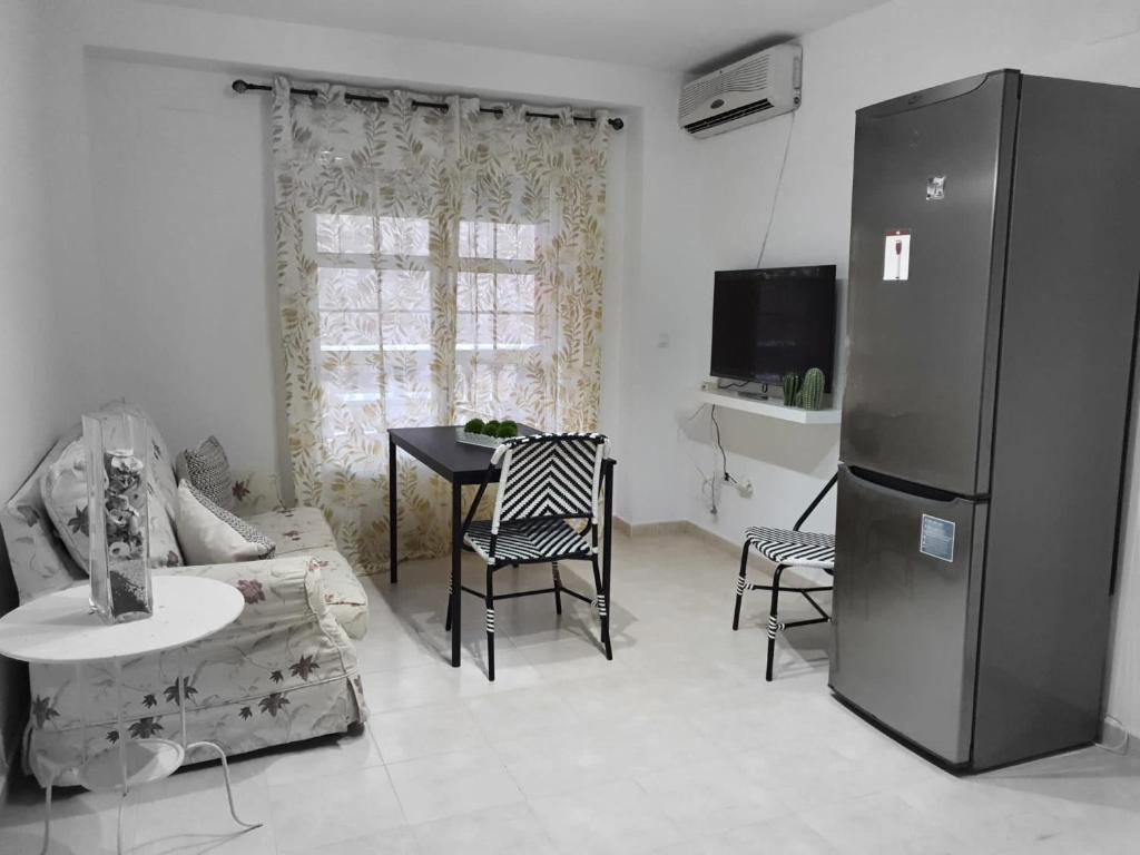 uma sala de estar com um frigorífico e uma mesa em Apartamento Puerto II em Mazagón