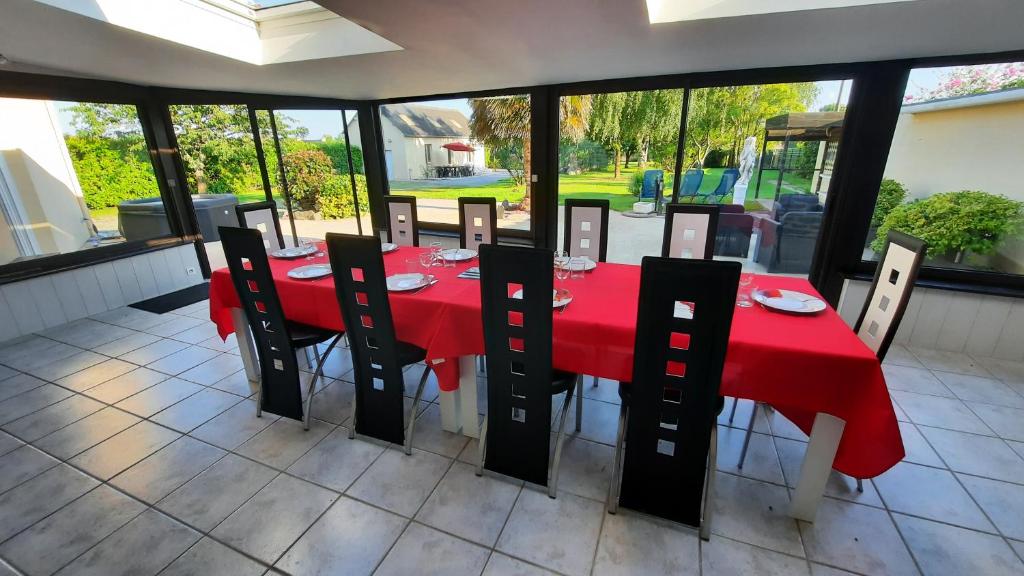 einem roten Tisch mit schwarzen Stühlen und einem roten Tischtuch in der Unterkunft Villa Excallibur, aux portes de Brocéliande in Carentoir