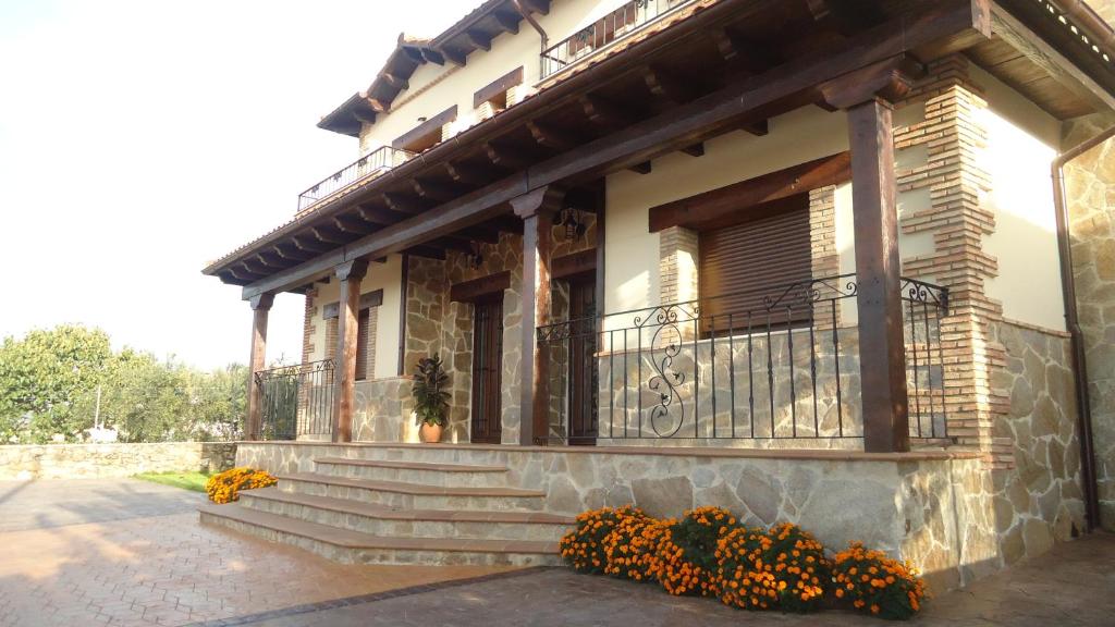 ein Gebäude mit einer Treppe und einem Balkon mit Blumen in der Unterkunft Casas Rurales El Caminante in Aldeanueva del Camino