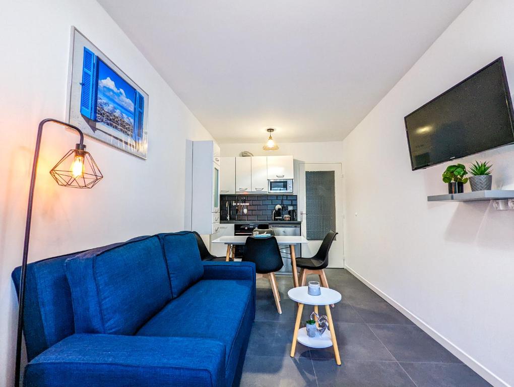 un salon avec un canapé bleu et une table dans l'établissement 1 Min to the Beach Apartment - Kitchen - Tramway - Air Conditioner - Wifi - Promenade Des Anglais, à Nice