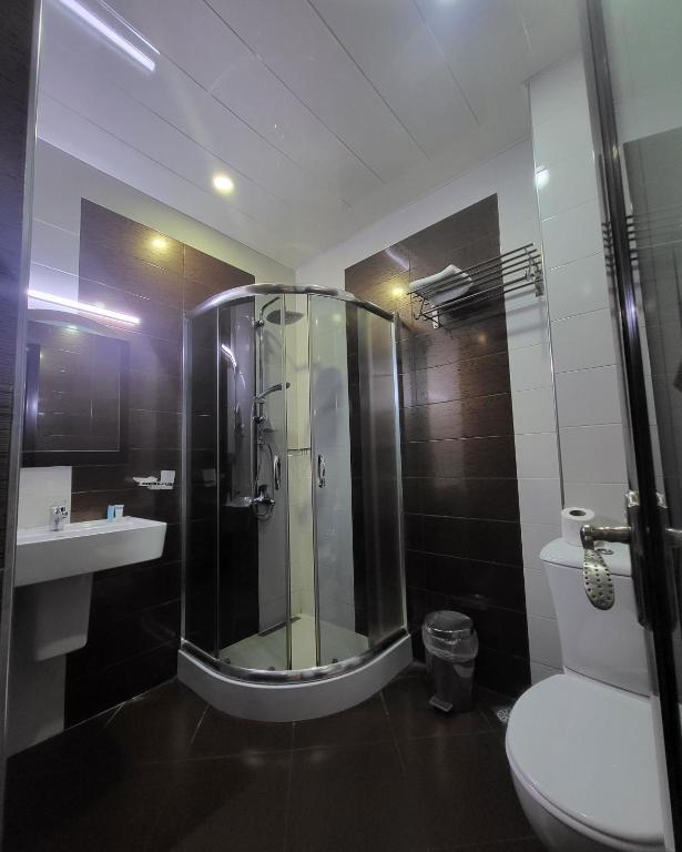 a bathroom with a shower and a toilet and a sink at Hotel Elio in Batumi