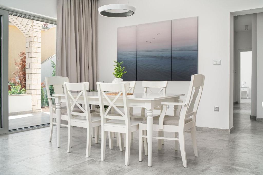 una sala da pranzo bianca con tavolo e sedie bianchi di Perla Luxury Apartment a Vodice