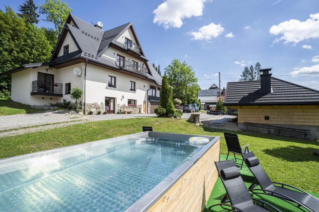 a house with a swimming pool in front of a house at Apartamenty U Jagielonki in Poronin