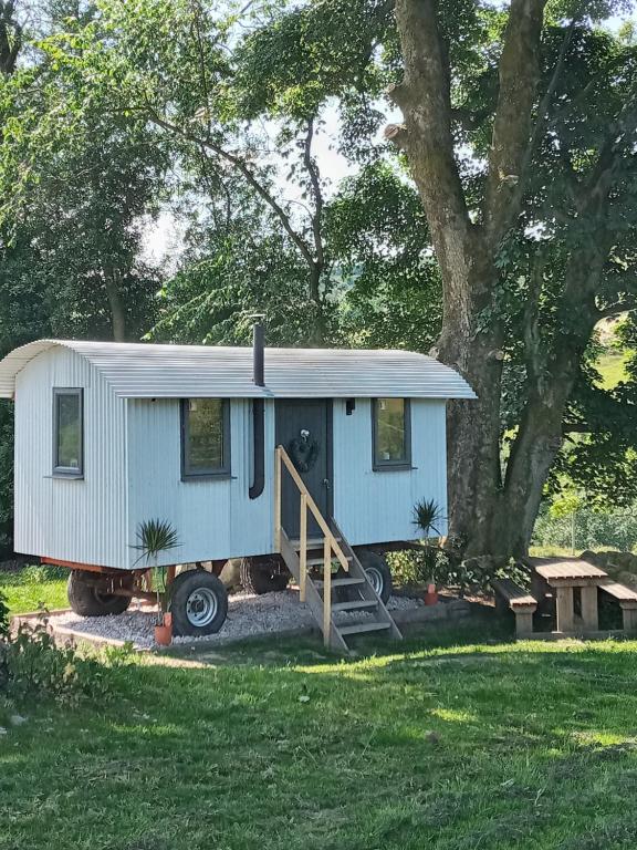 a blue tiny house parked in a yard at orchard meadow shepherd huts leek-buxton-ashbourne in Upper Elkstone