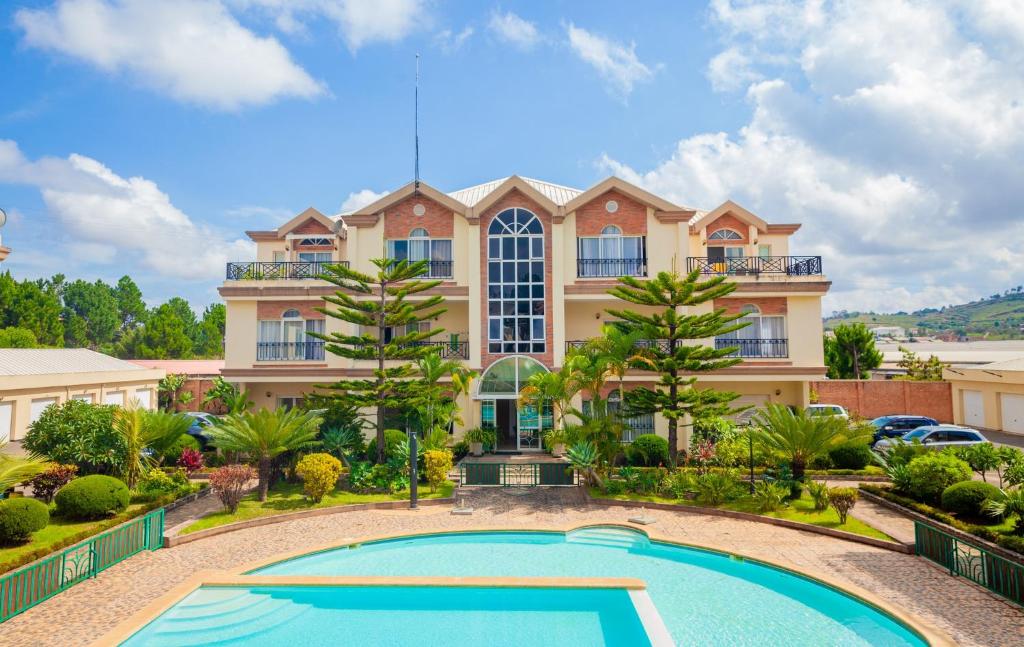 a large house with a swimming pool in front of it at Appartements - Le Paradisier Ambatobe in Antananarivo