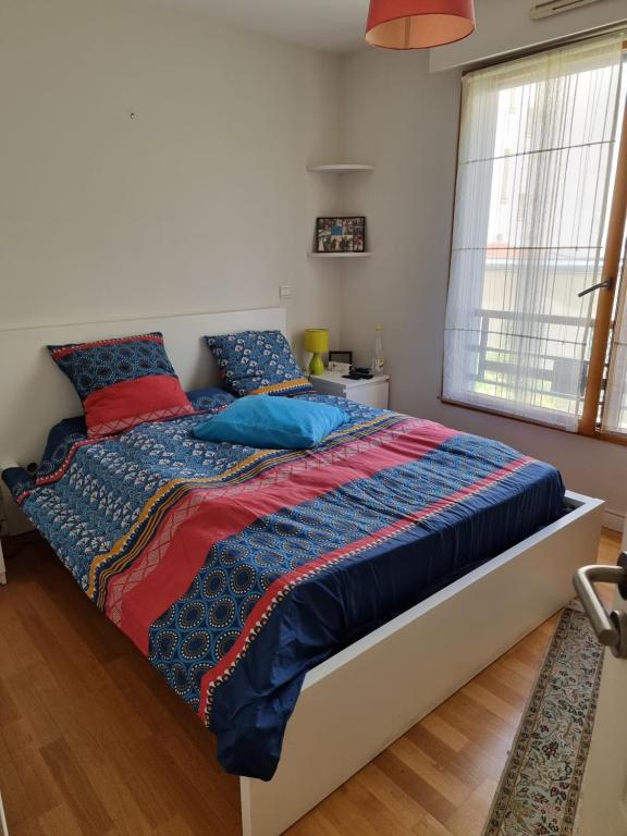 ein Bett mit blauen und roten Kissen in einem Schlafzimmer in der Unterkunft Appart Tour Eiffel pour 4 personnes in Paris
