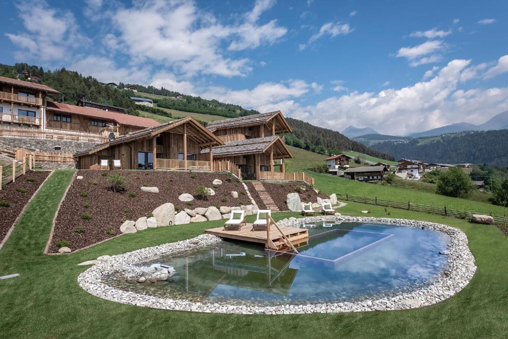 a pool in a yard with chairs and a house at DILIA Chalets & Apartments in Mühlbach