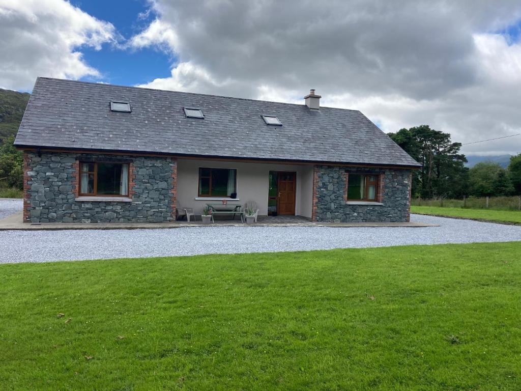 uma casa de pedra com um relvado em frente em Eagles Lodge em Killarney