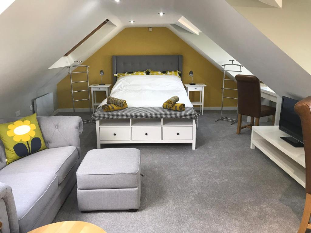 1 dormitorio con cama, escritorio y sofá en Round-y-Corner en Macclesfield