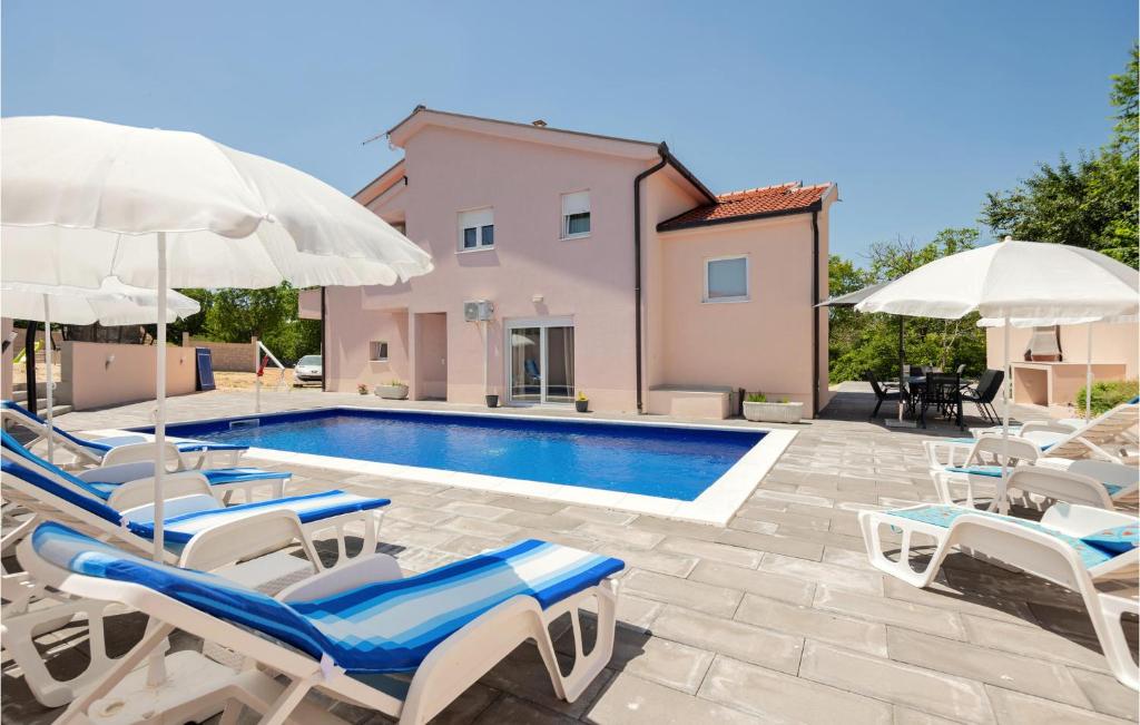 a pool with chairs and umbrellas next to a house at Gorgeous Home In Vinjani Gornji With Outdoor Swimming Pool in Nenadići