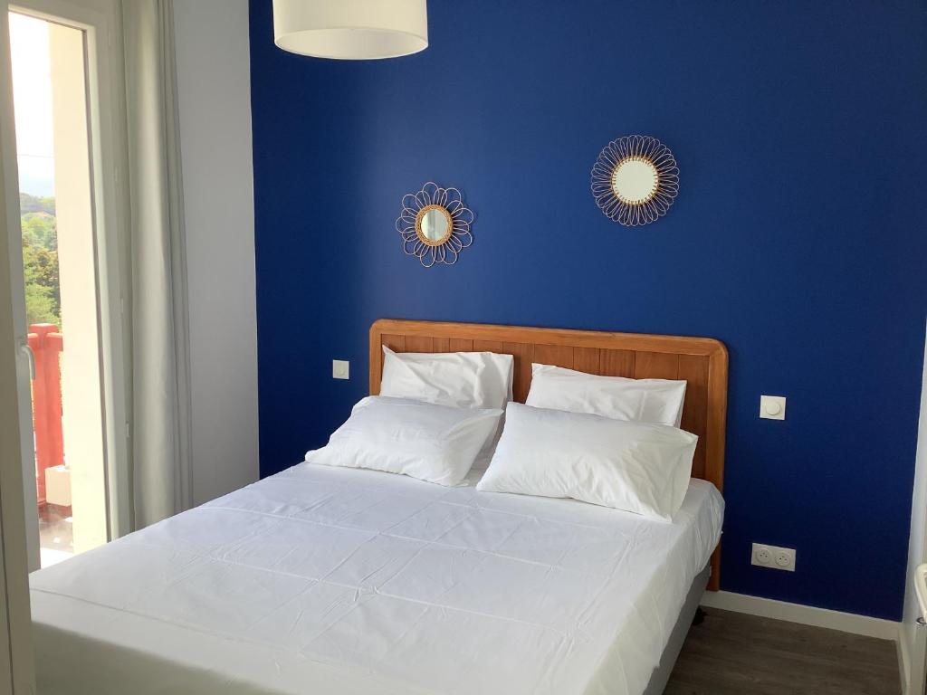 - une chambre bleue avec un lit et des oreillers blancs dans l'établissement Trinquet Bordatxo, à Saint-Jean-de-Luz