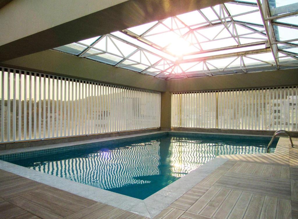 a swimming pool in a building with a large window at Apto a 200 m da Praia das Pitangueiras-Guaruja SP in Guarujá