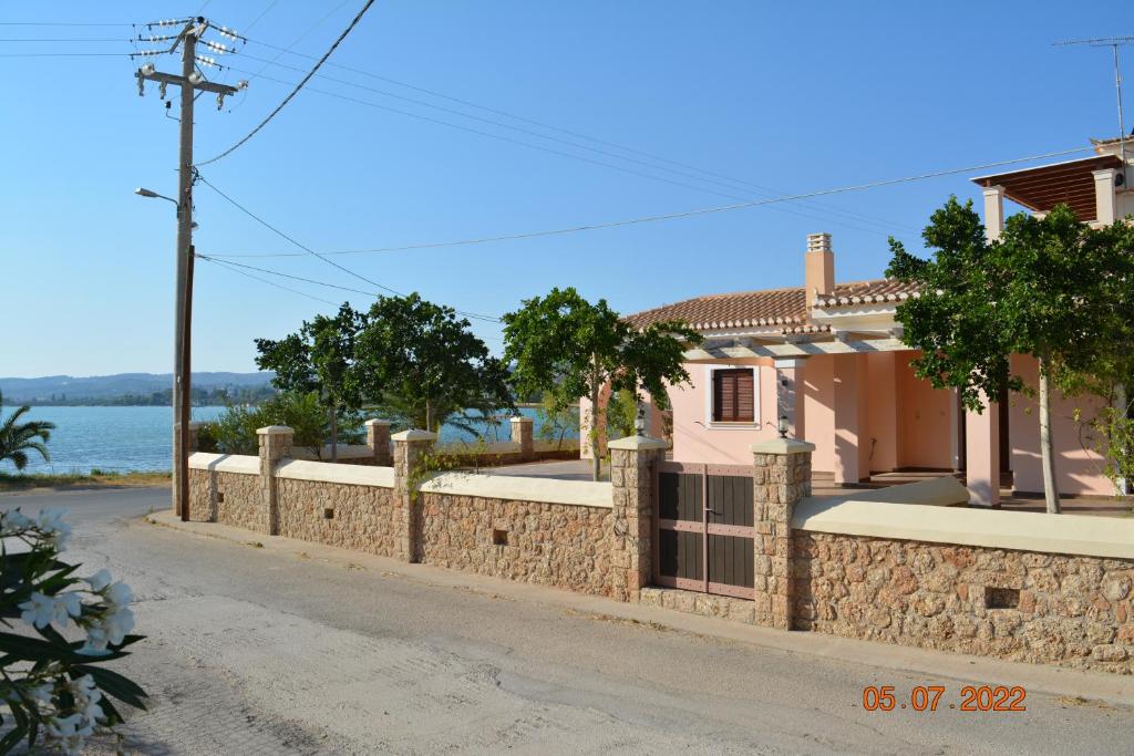 a house with a stone wall next to a street at Sunset Bay in Porto Heli