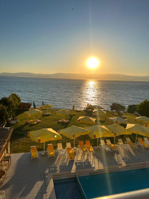 a group of yellow umbrellas and chairs next to a pool at Life Point Hotel in Çeşme