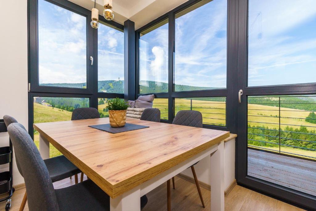 een eetkamer met een tafel en een aantal ramen bij Apartmán Dolce Vita Klínovec in Loučná pod Klínovcem