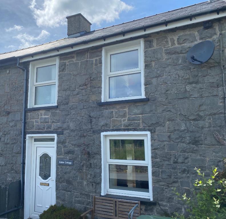 a stone house with a white door and windows at Antur Cottage in Blaenau-Ffestiniog