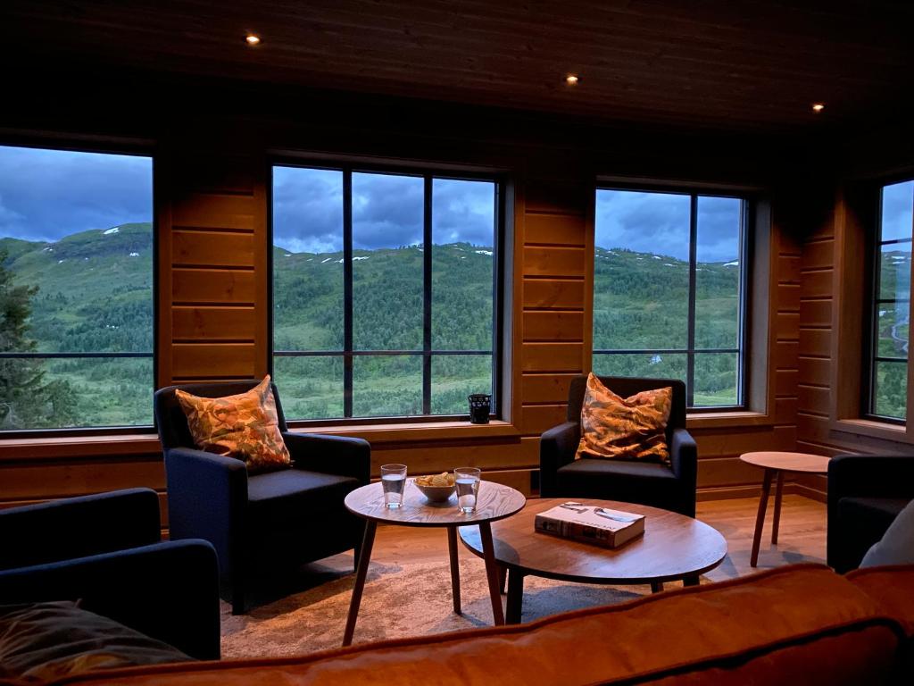 uma sala de estar com cadeiras, uma mesa e janelas em Hytte i Sogndal med panoramautsikt em Sogndal