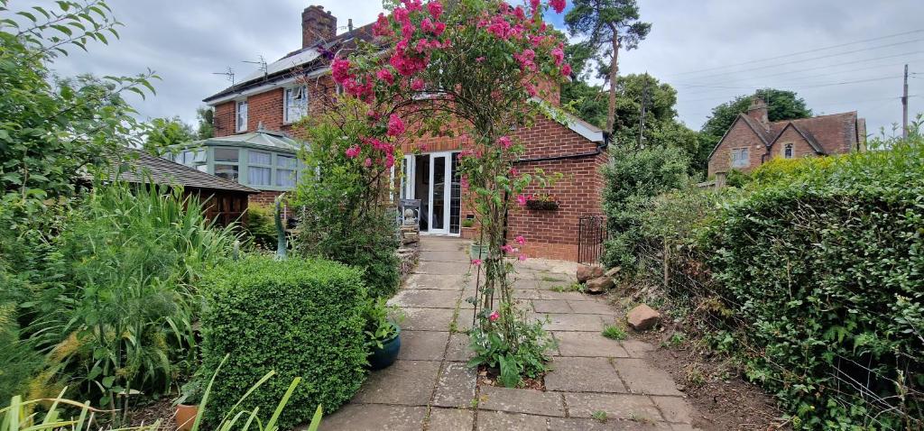 un jardín con flores rosas en una casa de ladrillo en Koi Pond Annex en Coleford