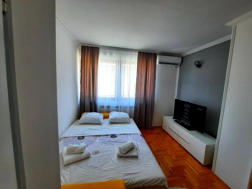 a small bedroom with two beds and a television at Apartment Denza City Center Sarajevo in Sarajevo