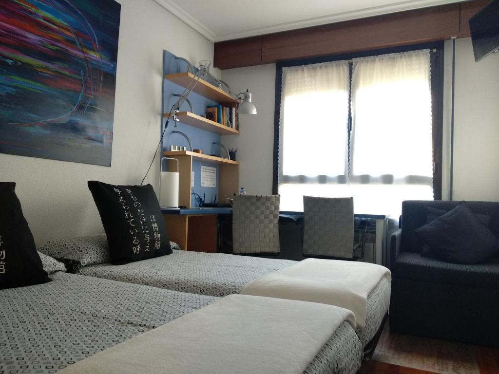 Habitación con 2 camas, silla y escritorio. en Wellington, en Vitoria-Gasteiz