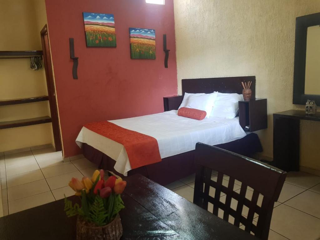 a hotel room with a bed and a table with flowers at El Patio de Don Moncho in Nueva San Salvador
