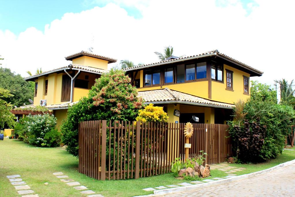 żółty dom z płotem przed nim w obiekcie Madalena Apart w mieście Praia do Forte
