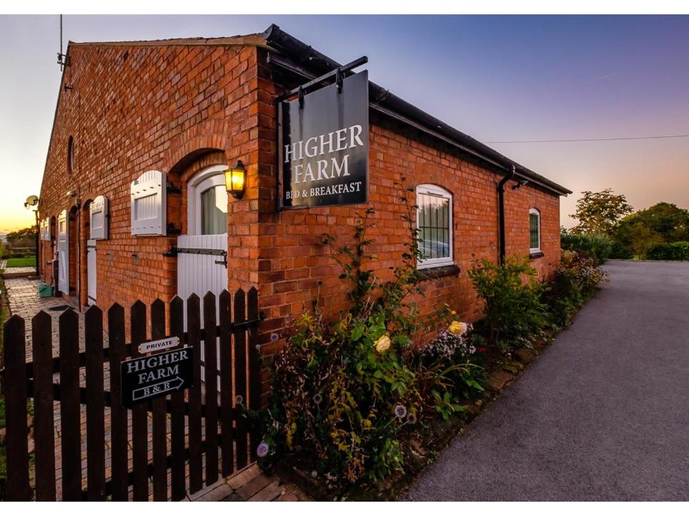 a brick building with a sign for a kitchen firm at Higher Farm in Malpas