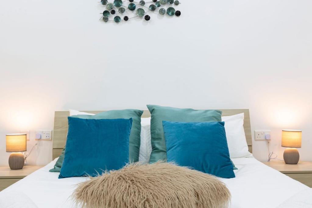 1 dormitorio con almohadas azules y 1 cama blanca en Brand new apartment in Sliema 2 min by the sea, en Sliema