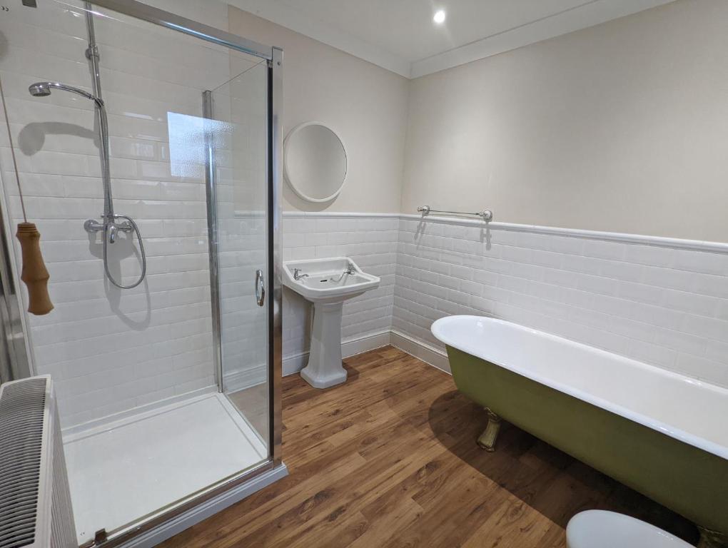 a bathroom with a shower and a tub and a sink at Gull Wing Guesthouse in Lowestoft