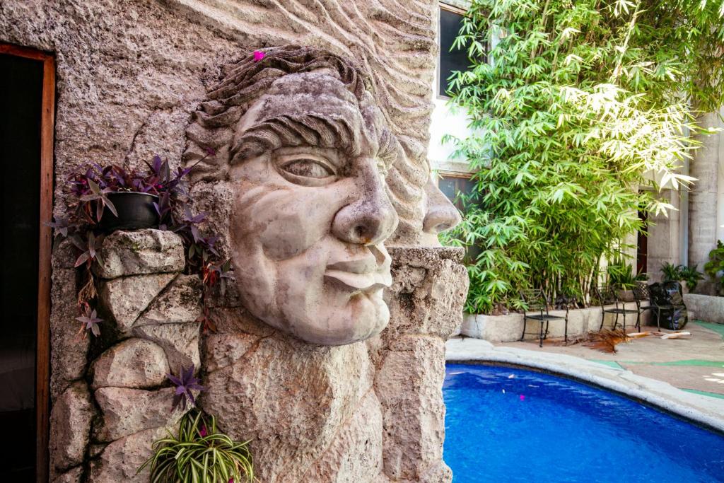 una statua di un volto accanto alla piscina di Villa Serena Centro Historico a Mazatlán