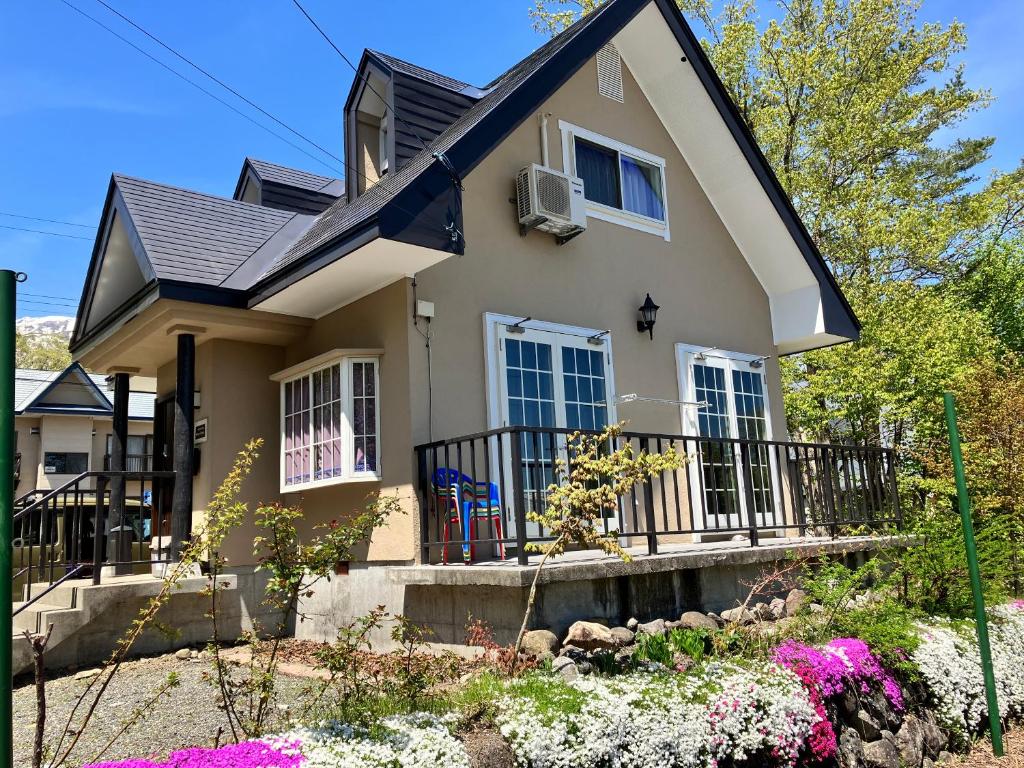 a house with a balcony and flowers in front of it at Kotori Cottage in Hakuba