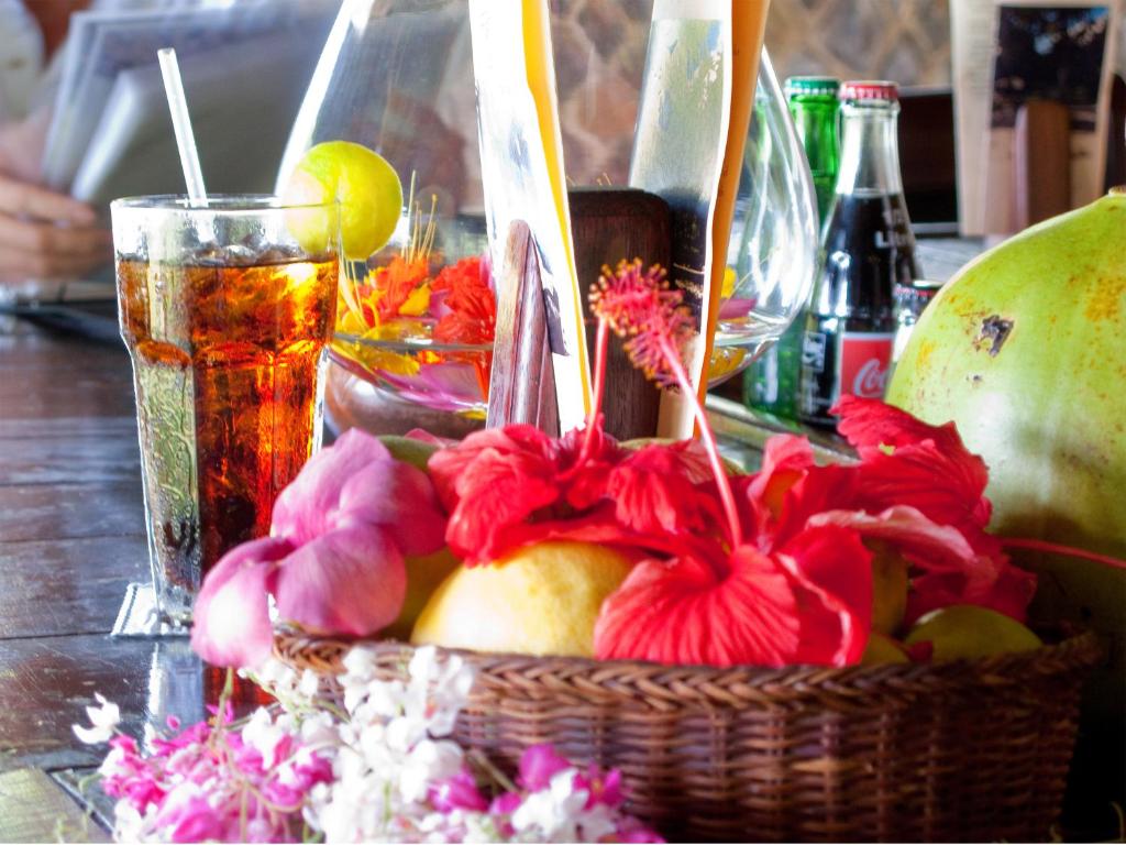 a basket of fruit and flowers on a table with a drink at Firefly Estate Bequia in Crescent Beach