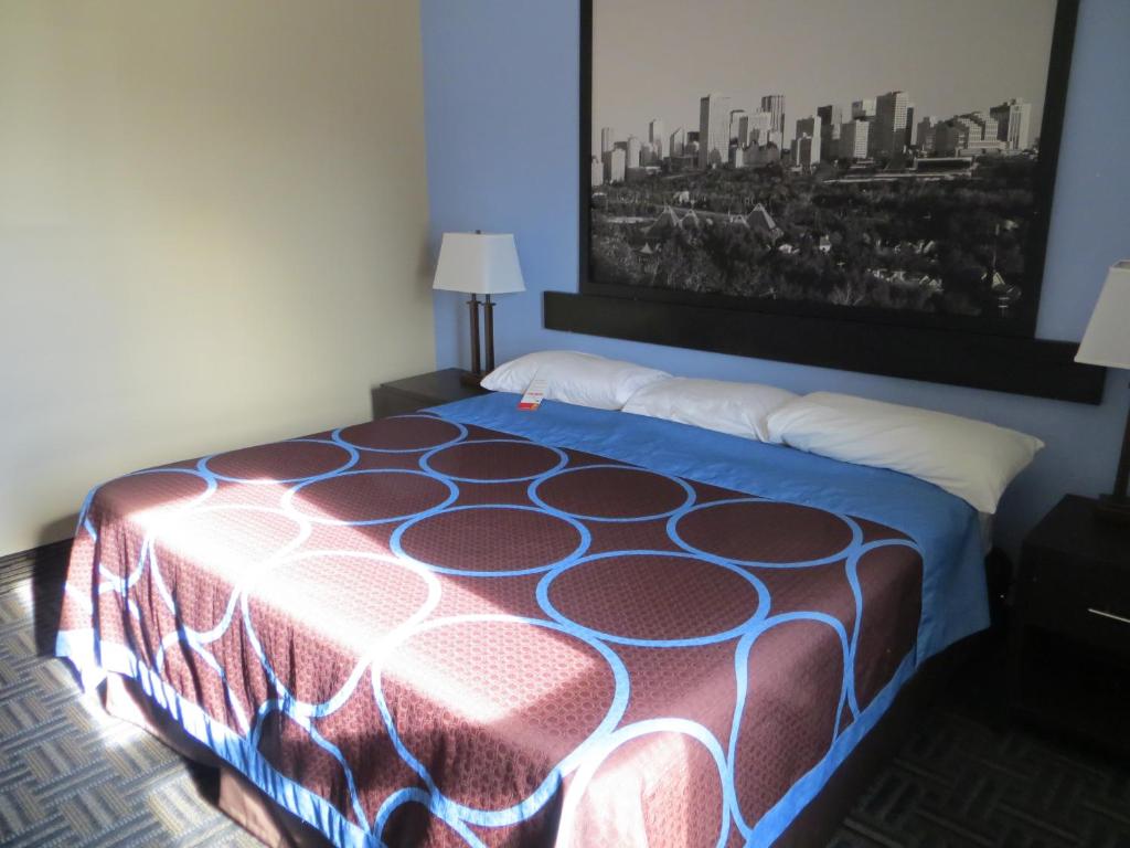 a bed in a room with a painting on the wall at Super 8 by Wyndham Edmonton/West in Edmonton