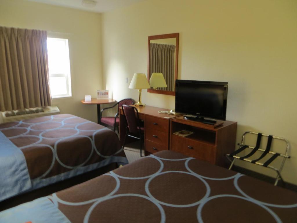 a hotel room with a bed and a flat screen tv at Super 8 by Wyndham Edmonton/West in Edmonton