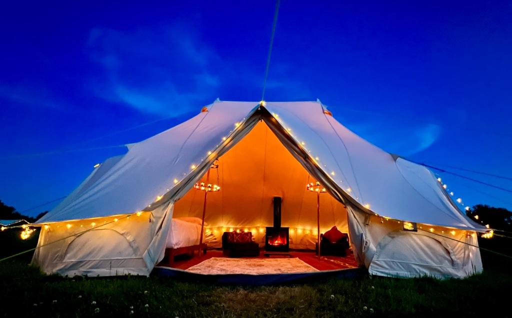 a white tent with lights in a field at night at Hartridge Springs in Honiton