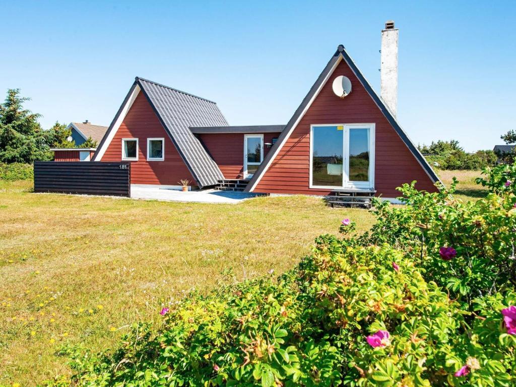 a home with a red house on a grass field at 6 person holiday home in Hvide Sande in Hvide Sande