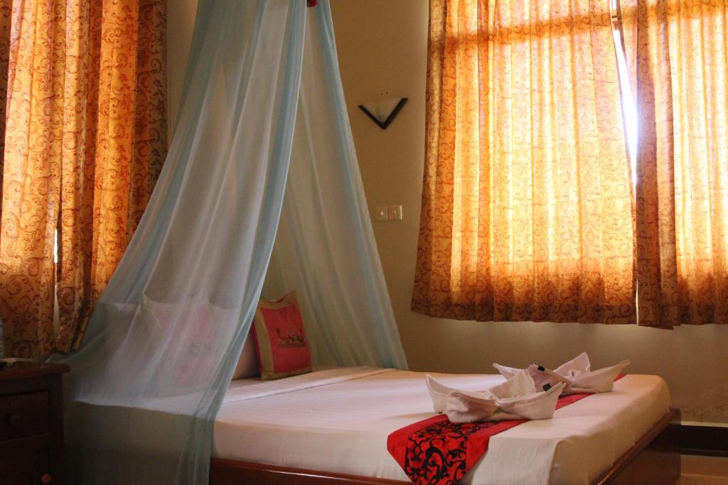 a bed with a mosquito net in a room with windows at Golden Noura Villa-Pub & Restaurant in Phnom Penh