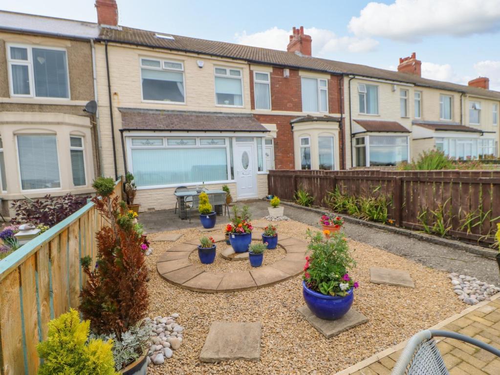a backyard with potted plants and houses at Beach Cove View in Newbiggin-by-the-Sea