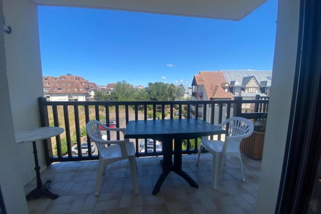 un patio avec une table et des chaises sur un balcon dans l'établissement 23m paisible avec balcon près de la plage !, à Cabourg