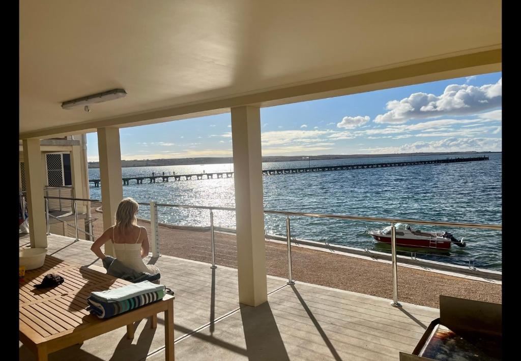 Una donna seduta sul ponte di una barca di Beachside & Jetty View Apartment 1 - Admirals Apartment a Streaky Bay