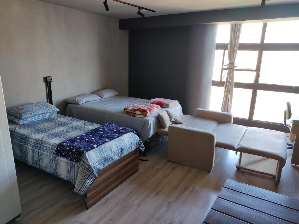 a room with two beds and a chair and a window at Espaço aconchegante - Centro - São Paulo in Sao Paulo